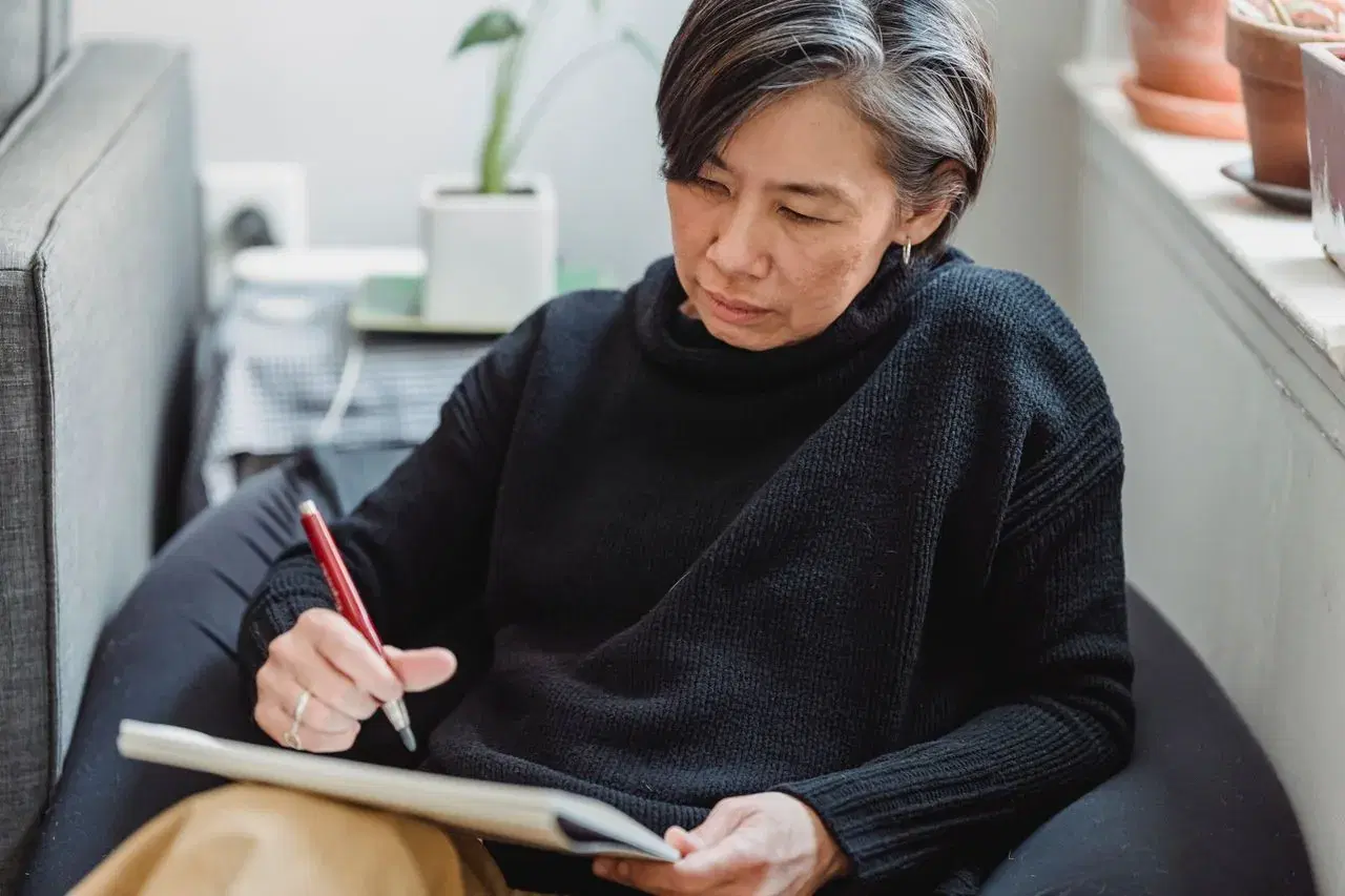 A woman sitting on a couch, writing in a workbook